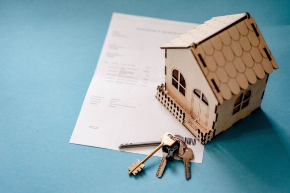Maquette de maison en bois et clés posées sur des documents officiels, idéales pour un devis assurance habitation en ligne.