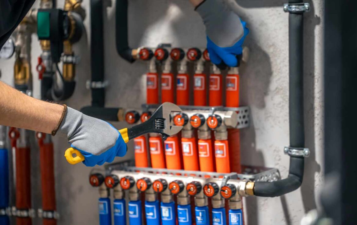 Un technicien en gants de protection manipule une clé à molette sur un réseau hydraulique pour un entretien filtre chauffage pompe à chaleur.