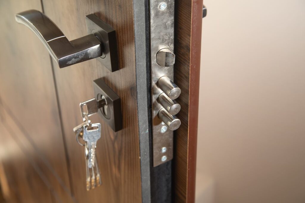 Gros plan sur la tranche d'une porte d'entrée en bois massif ouverte, montrant une serrure de haute sécurité multipoints avec ses pênes en acier sortants et une clé insérée dans le cylindre. Cette installation illustre parfaitement le travail d'un professionnel pour installer verrou de blocage supplementaire serrurier paris sur un appartement.